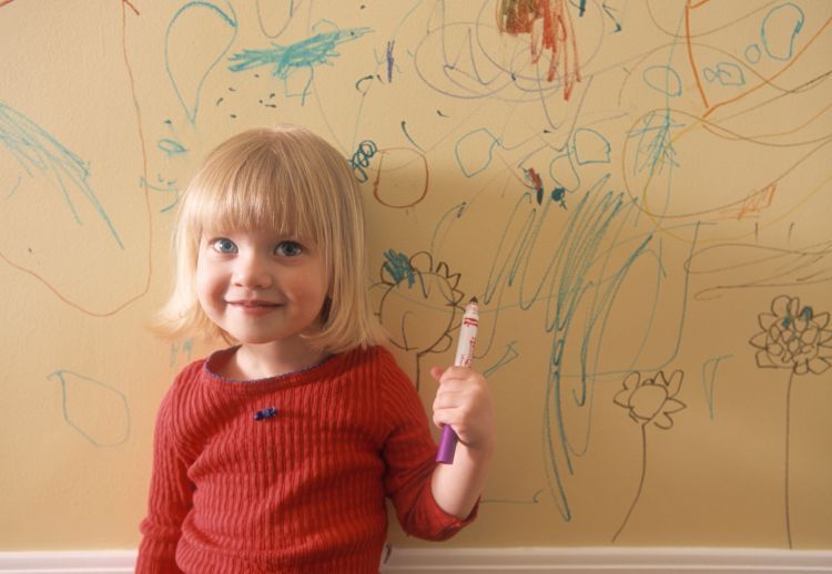 AAKT0C little girl writing on the wall of her house