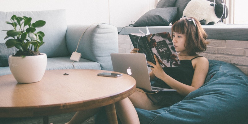 women sitting on bean bag using MacBook