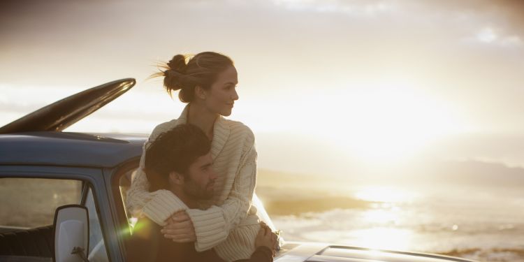 Serene couple hugging on truck at beach