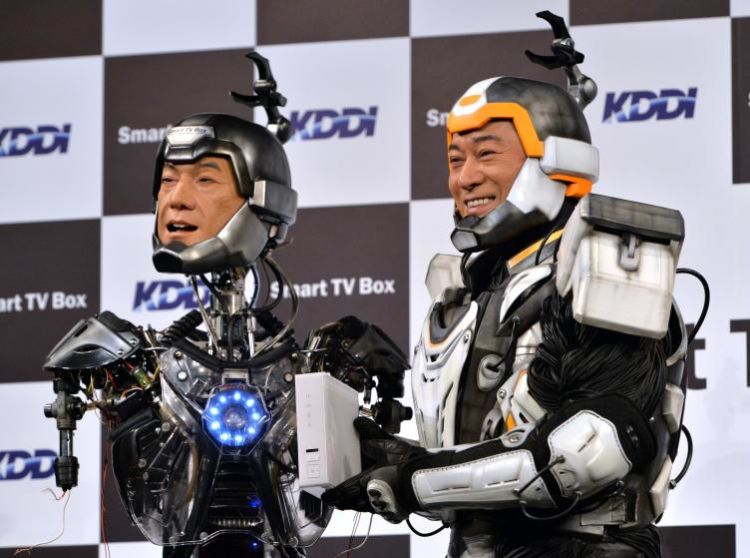 Japanese actor Ken Matsudaira (R), clad in a robot suit, smiles with an android robot (L) in his likeness called
