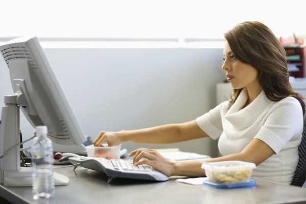 Young businesswoman eating lunch at desk