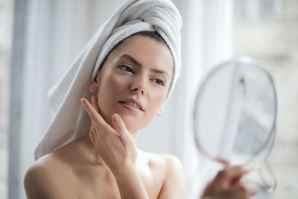Wanita yang sedang mengoleskan skincare di wajahnya